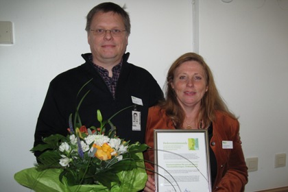 Jörgen Malmros har en blombukett i famnen och Christina Pernholt en tavla med prismotiveringen på.