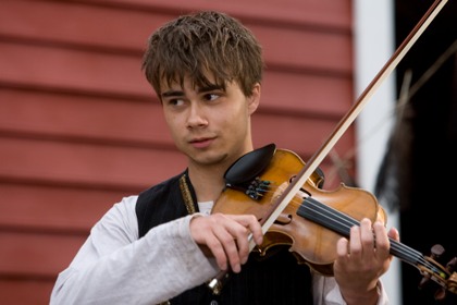 Alexander Rybak har en roll i den påkostade norska filmen Yohan. På bilden spelar Alexander fiol. Han har mörk kort hår med lång lugg och markerade ögonbryn.