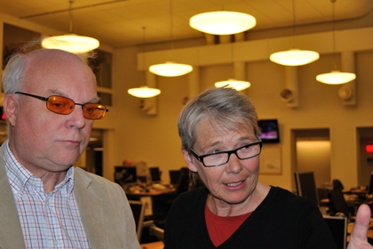 Göran Ringblom har vitt hår och orangea glasögon. Marianne Hasslow har kort grått hår och långsmala glasögon.