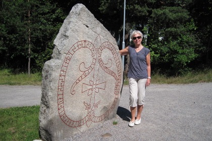 Jarlabankes bro med runsten i granit med tegelröda runor från cirka 1050 efter Kristus. Astrid McCormack står invid runstenen.