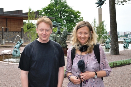 Johan Rosengren har brunt, ganska kort hår och svart t-shirt, Åsa Nilsson har axellångt blont hår, lila blus, håller i en mikrofon i handen och ler.