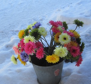 En färgglad blomsterbukett i snön värmer i vinterkylan.