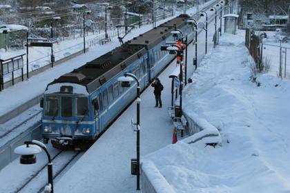 Foto: Veronica Edström. I ett vinterlandskap ankommer det blå lokaltåget till den nya stationen Universitetet på Roslagsbanan.