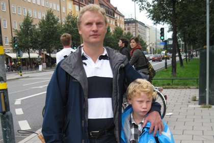 Boris Samuelsson och hans sjuårige son Emil har båda ljust lockigt hår. På bilden står de vid övergångsstället vid den hårt trafikerade Ringvägen i Stockholm.