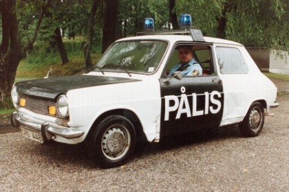 Bild på gammal polisbil med texten ”Pålis” målad på sidan av bilen.