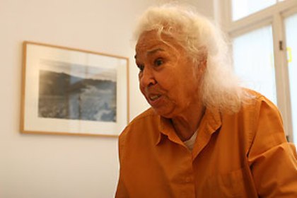 Nawal El Saadawi har vitt halvlångt lockigt hår och en orange skjorta.