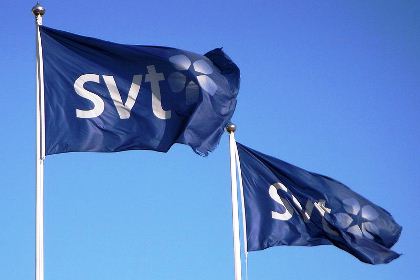 Två flaggor med texten SVT mot en blå himmel.