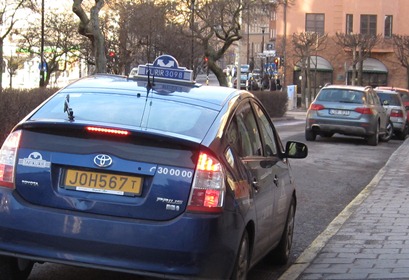 En taxibil invid vägkanten, fotograferad bakifrån