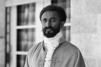 Haile Selassie har svart hår och skägg, mörk hy och är klädd i en högtidsdräkt i arabisk stil.