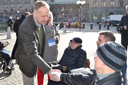 Jonas Sjöstedt (V) skakar hand i grön kavaj.