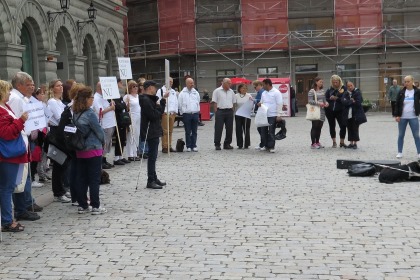 Människor som står på ett torg. De håller i plakat.