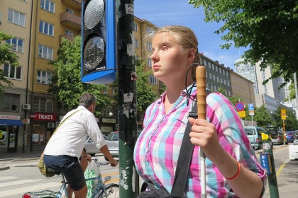 En kvinna under trafikljuset, som är blått med två cirklar där lampor visar siffror.